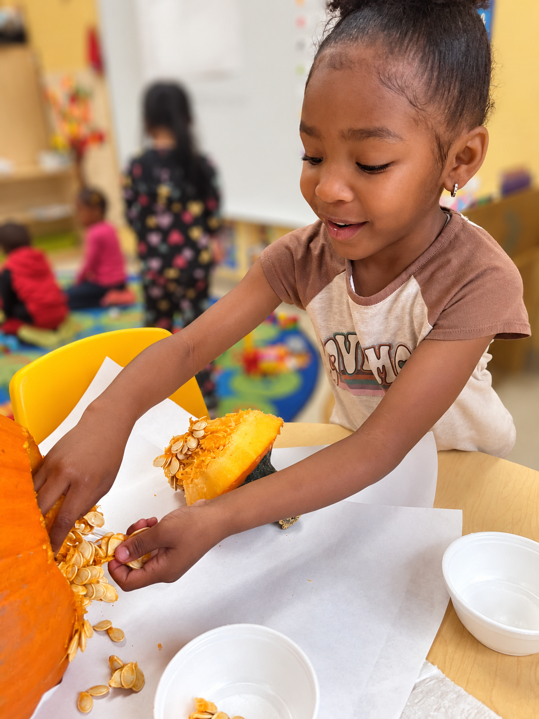 Child exploring the inside of a pumpkin and its seeds during a classroom discovery activity