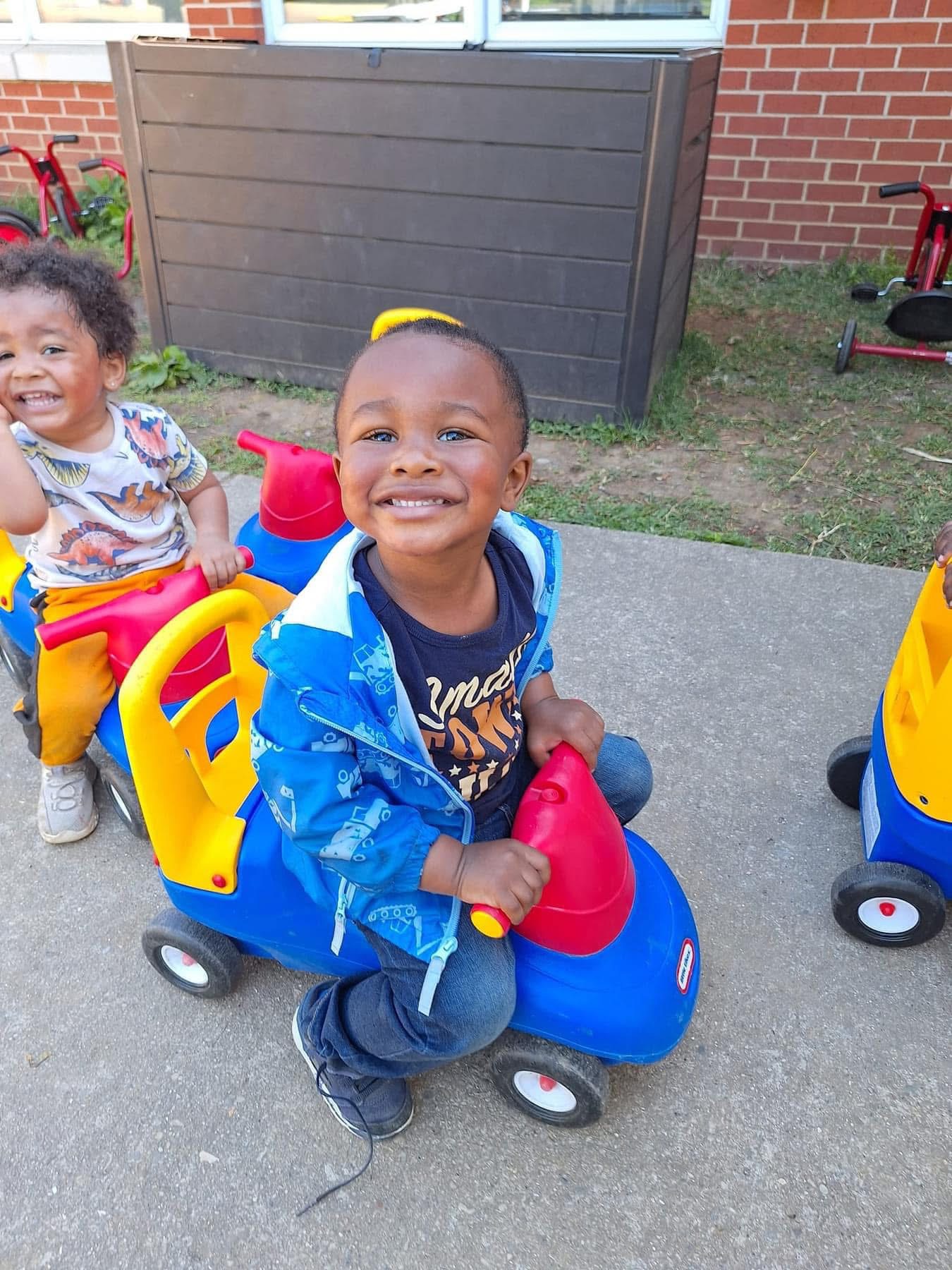 A toddler enjoys an outdoor ride-on toy.